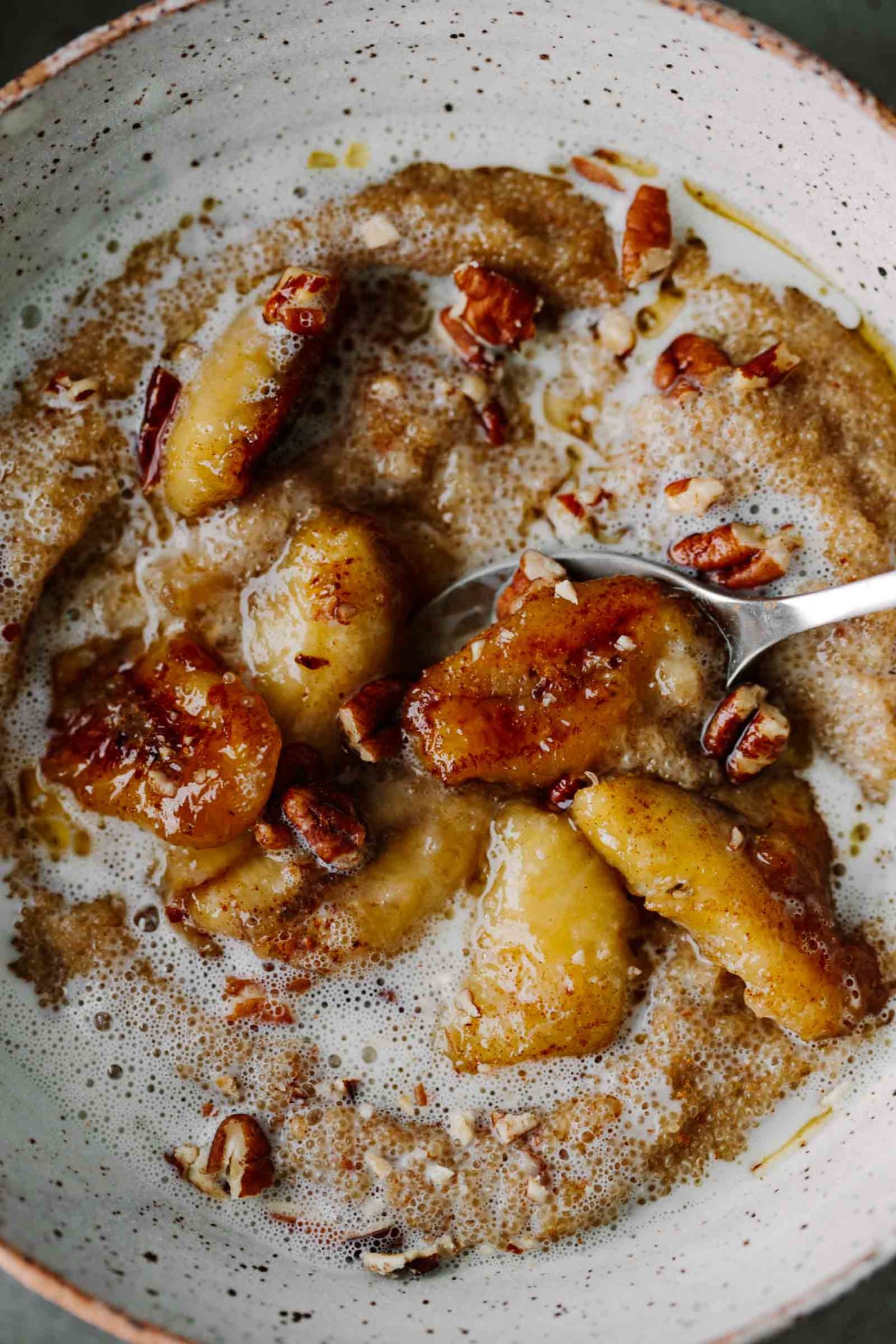 Close-up photo of amaranth porridge topped with caramelized bananas and extra cream.