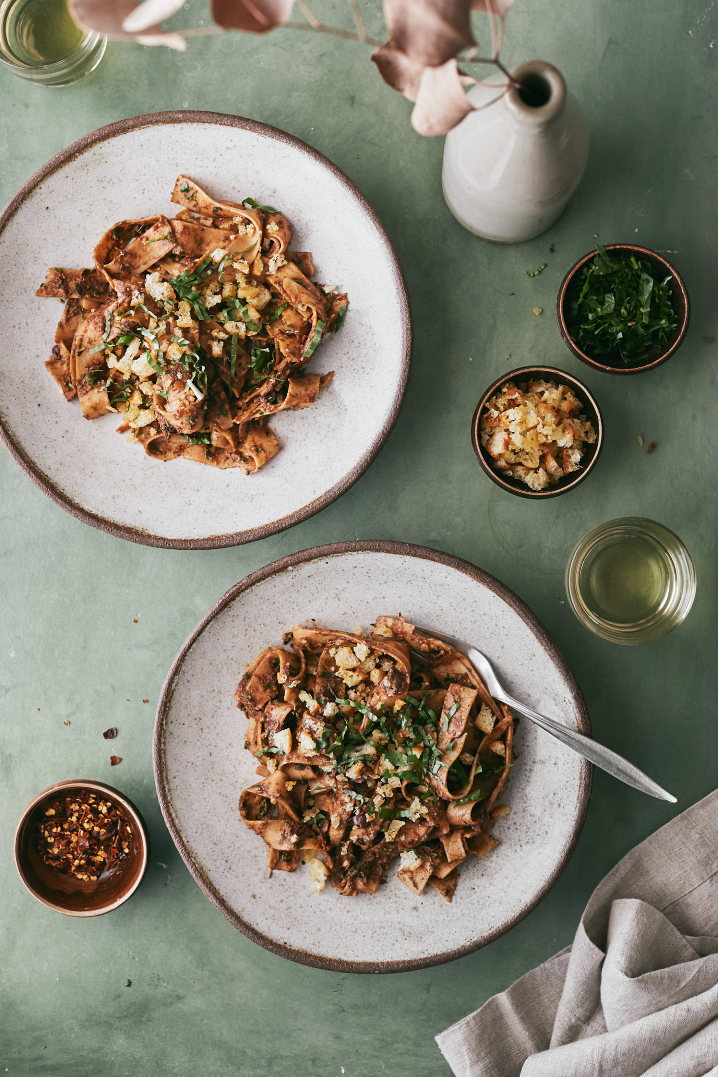 Two bowls of pasta on a dark green background.