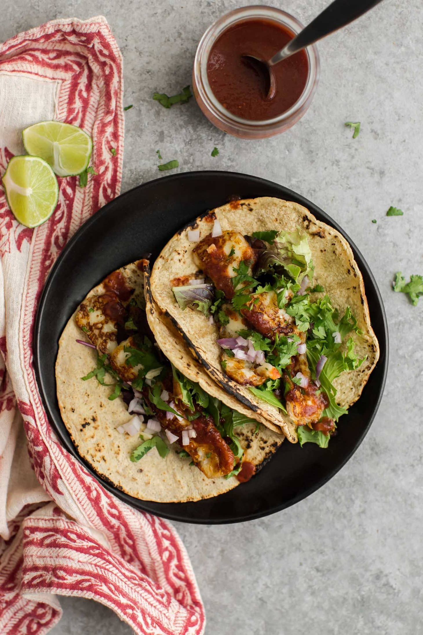 Overhead photo of two halloumi tacos on a dark plate