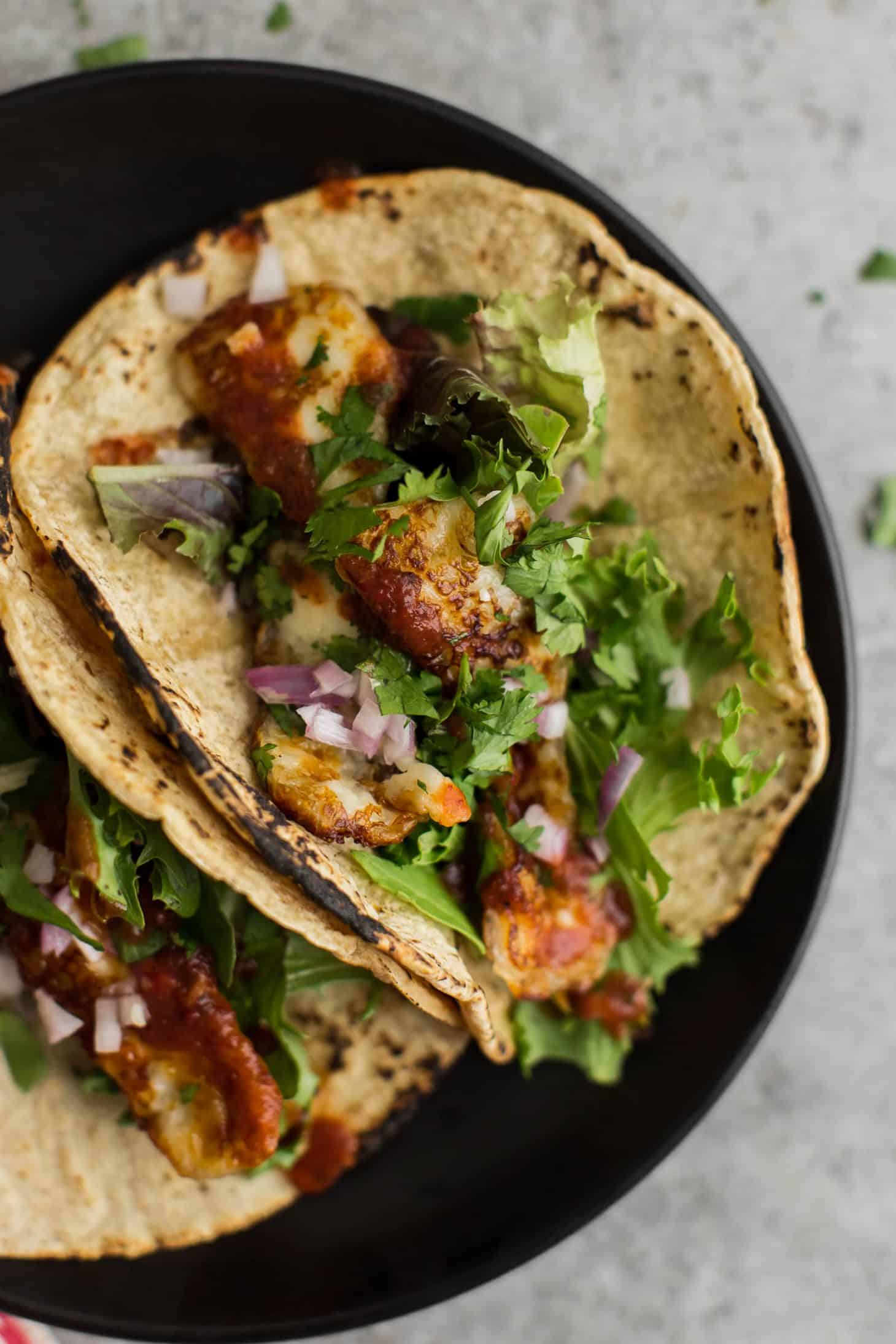 Overhead shot of pan-fried halloumi in tortillas on a dark plate