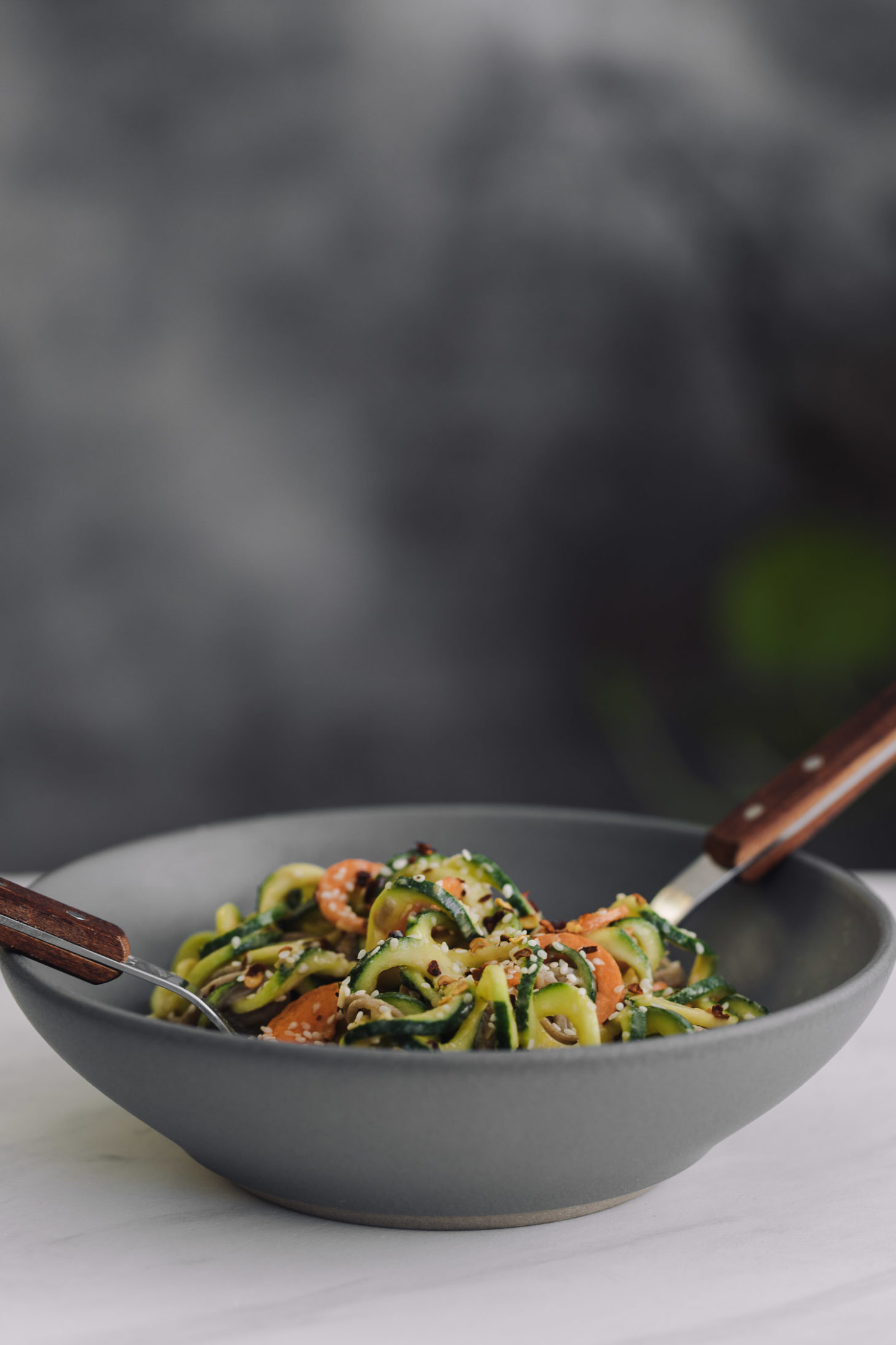 Side-angle shot of spiralized carrots and zucchini tossed with noodles and tahini sauce.