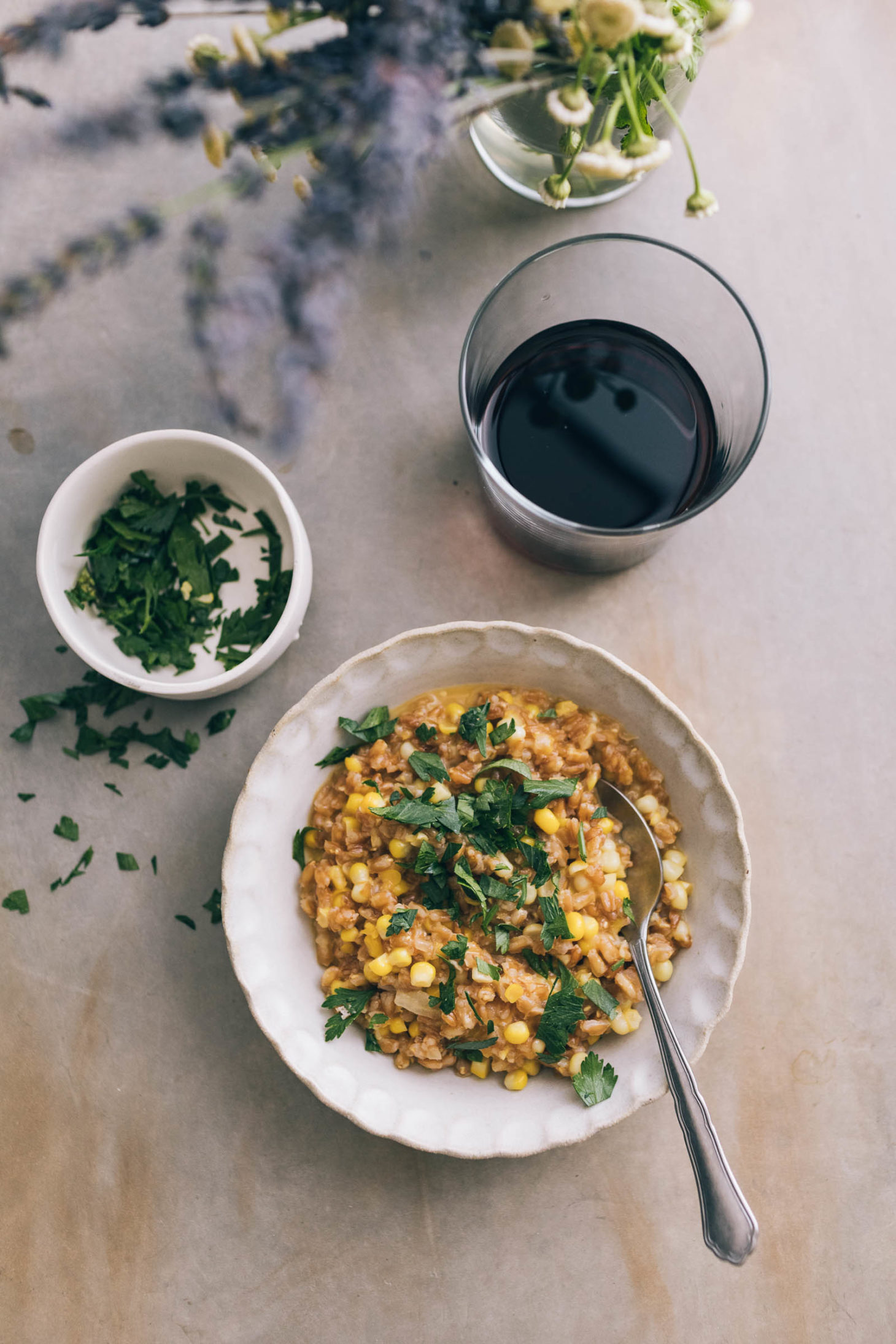 Overhead shot of a cream bowl of baked farro risotto topped with parsley