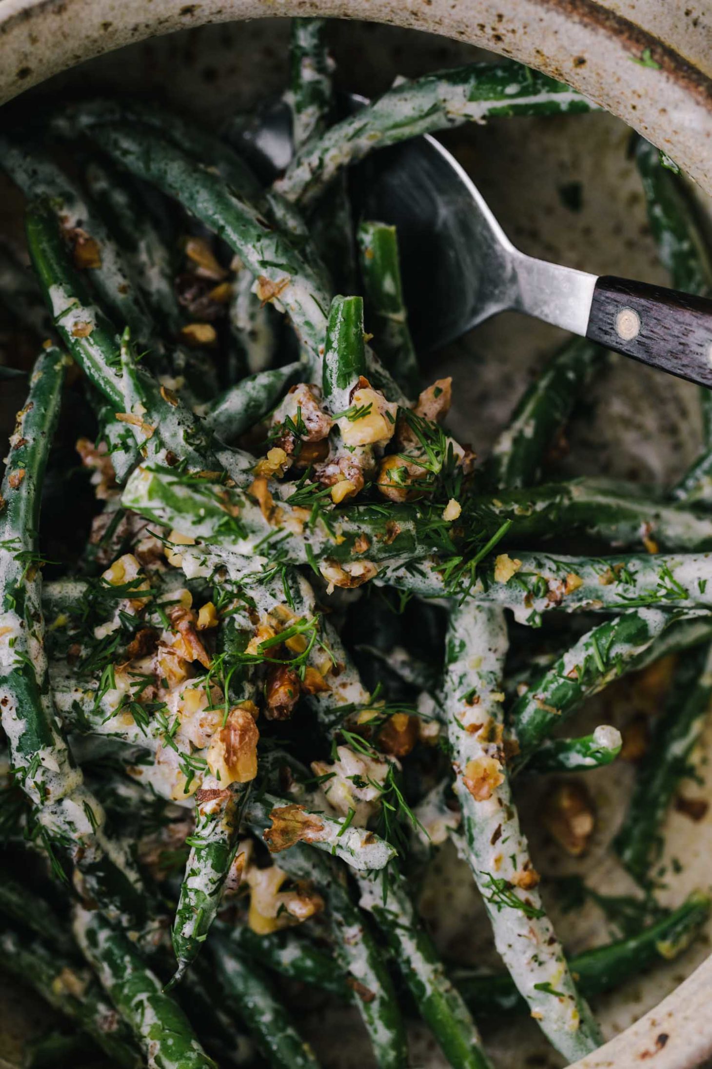 Side Angle Photo of yogurt green beans that have been blanched and tossed with walnuts and yogurt sauce.