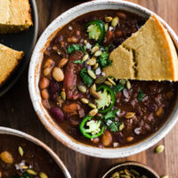 Overhead close-up view of vegan chili with cornbread and jalapenos