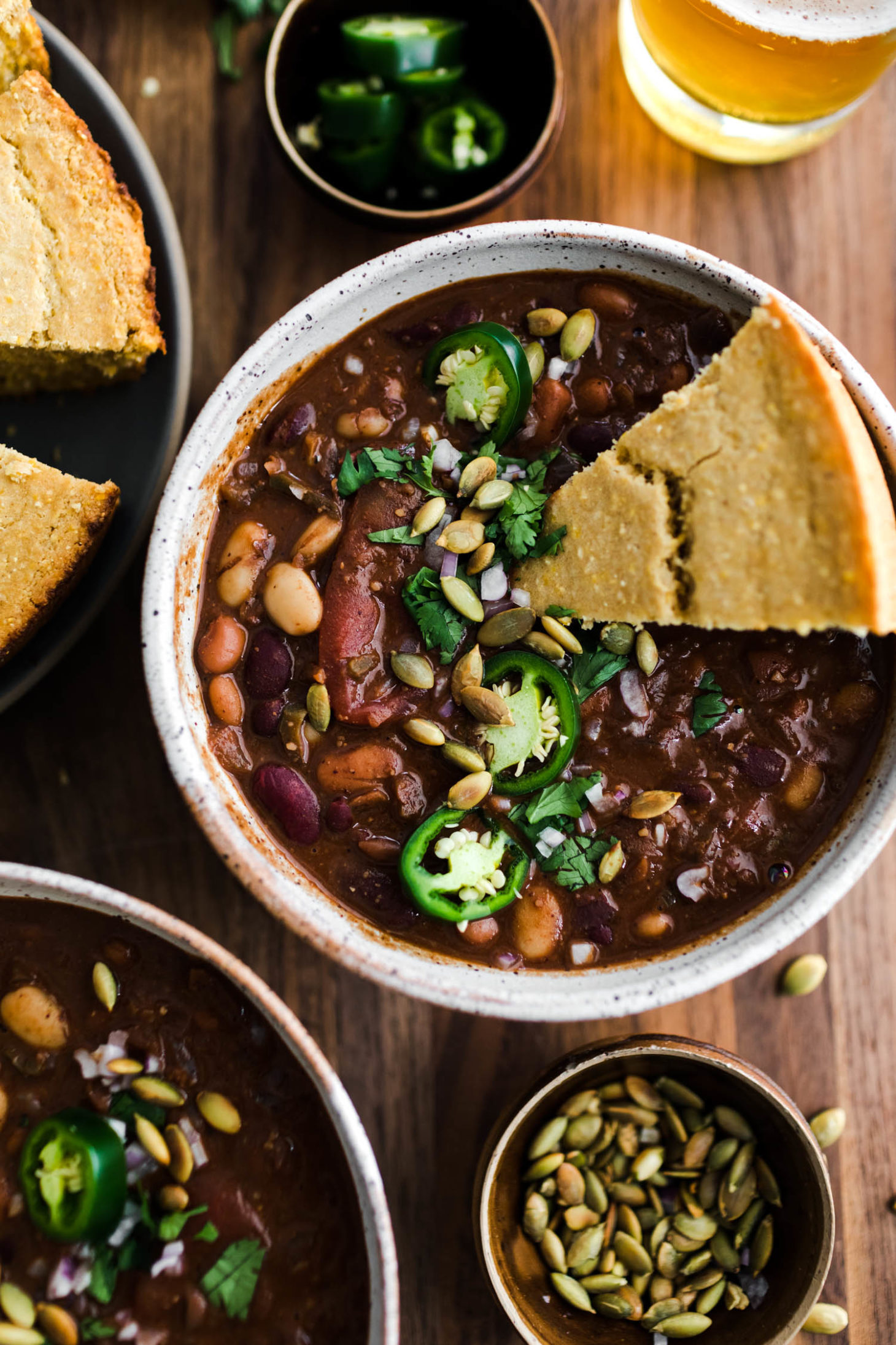 Overhead close-up view of vegan chili with cornbread and jalapenos