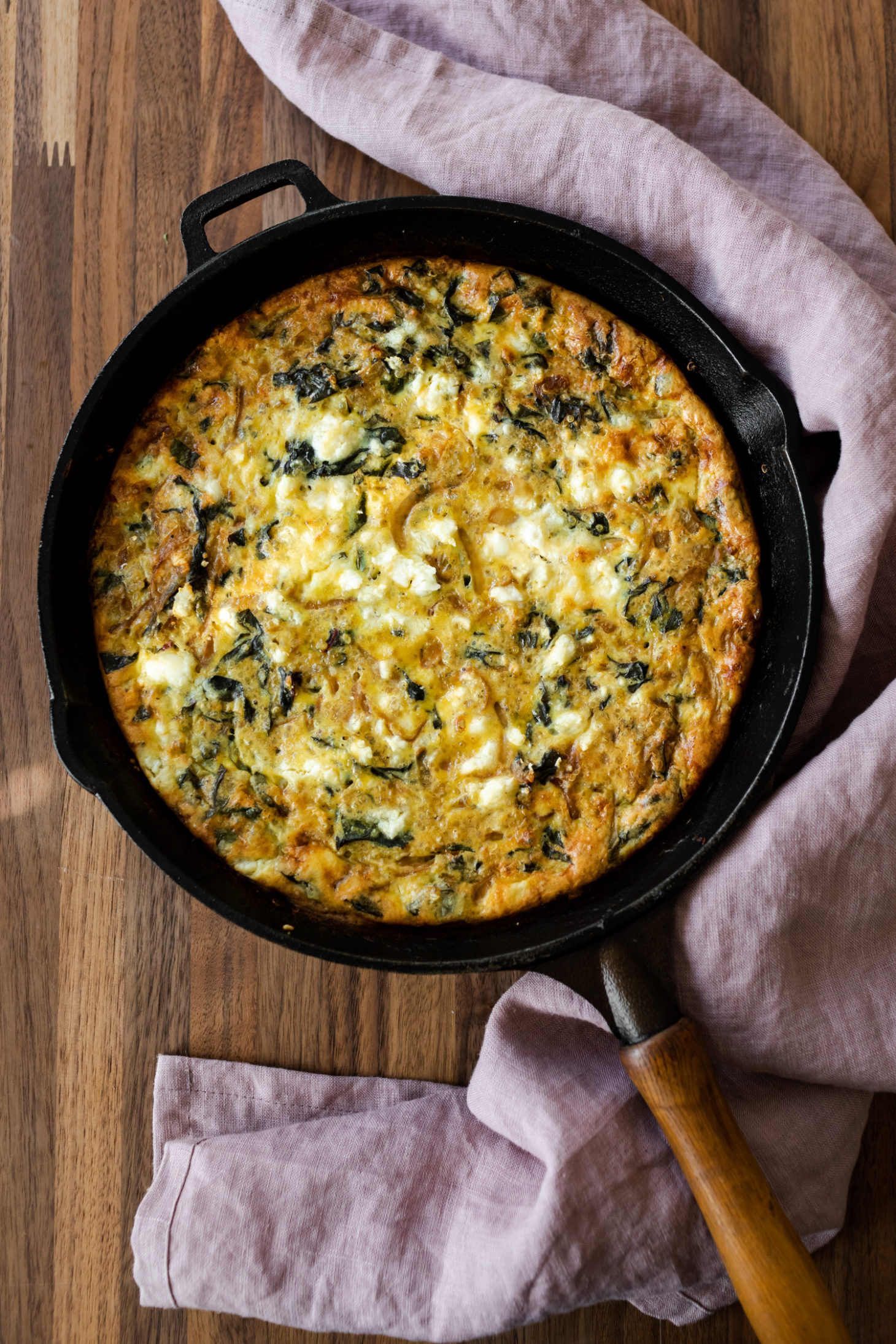 Overhead shot of a quinoa chard frittata on a wood countertop