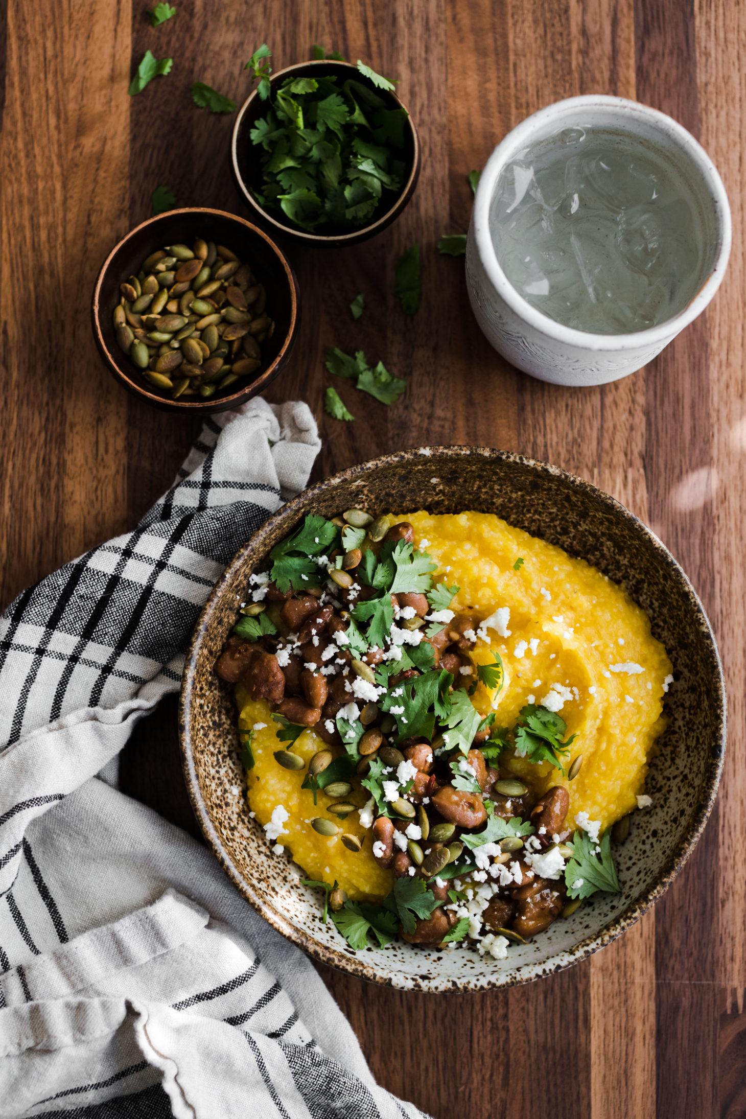 Overhead photo of pumpkin polenta topped with pinto beans, pepitas, and feta.