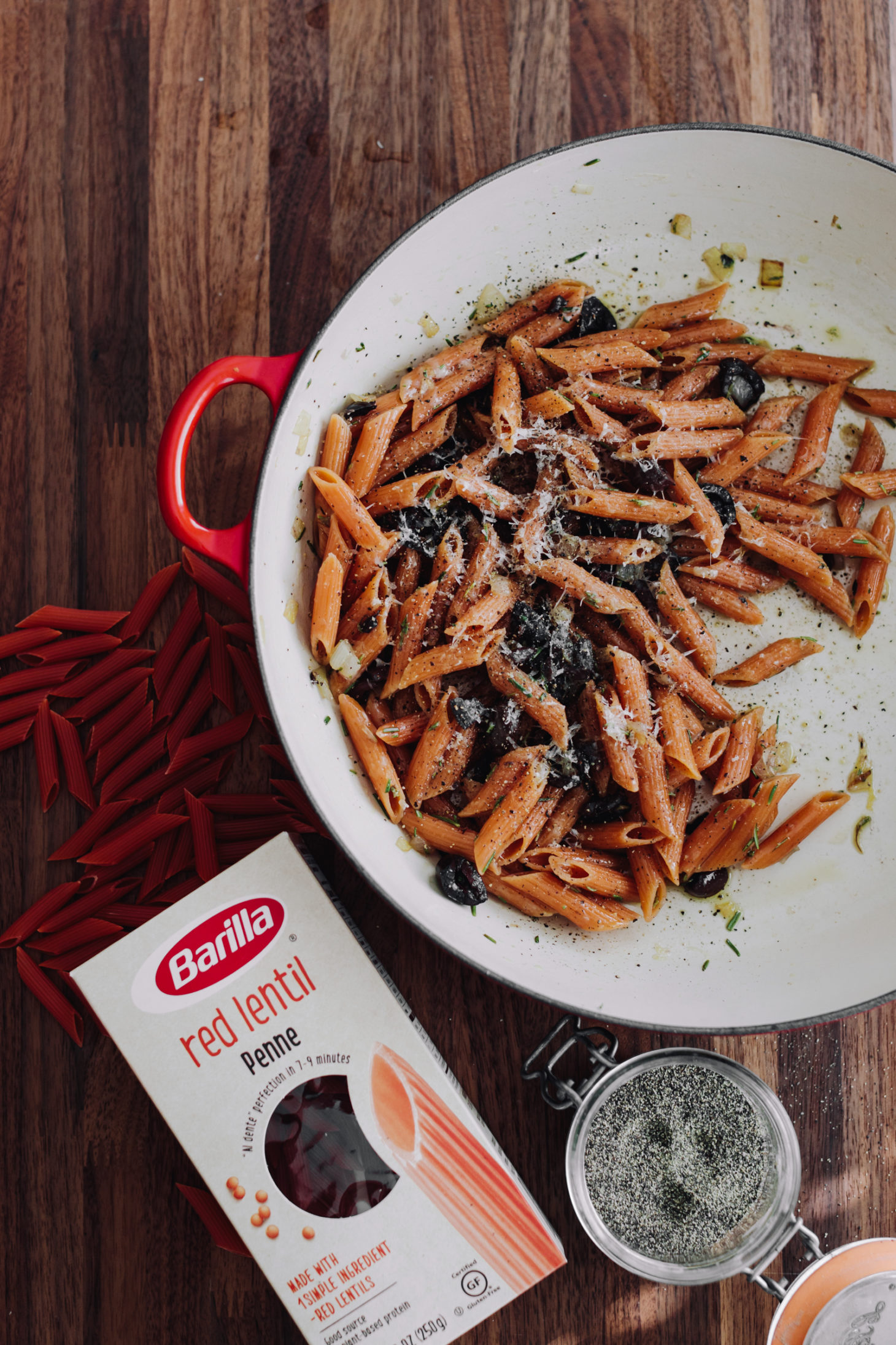 Overhead photograph of red lentil pasta with olives and a box of barilla pasta.