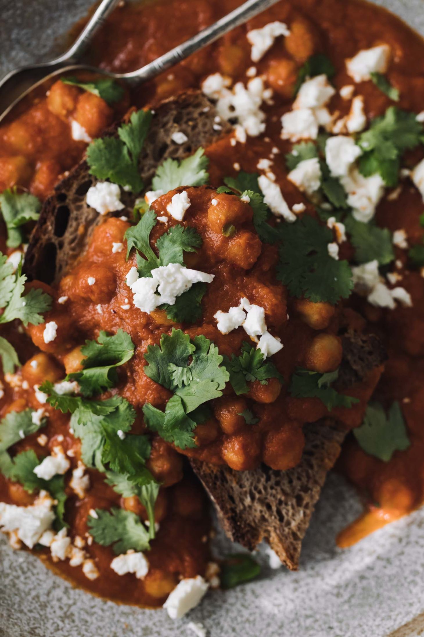 Overhead shot of chickpeas in a rich tomato sauce, all on a piece of toast.