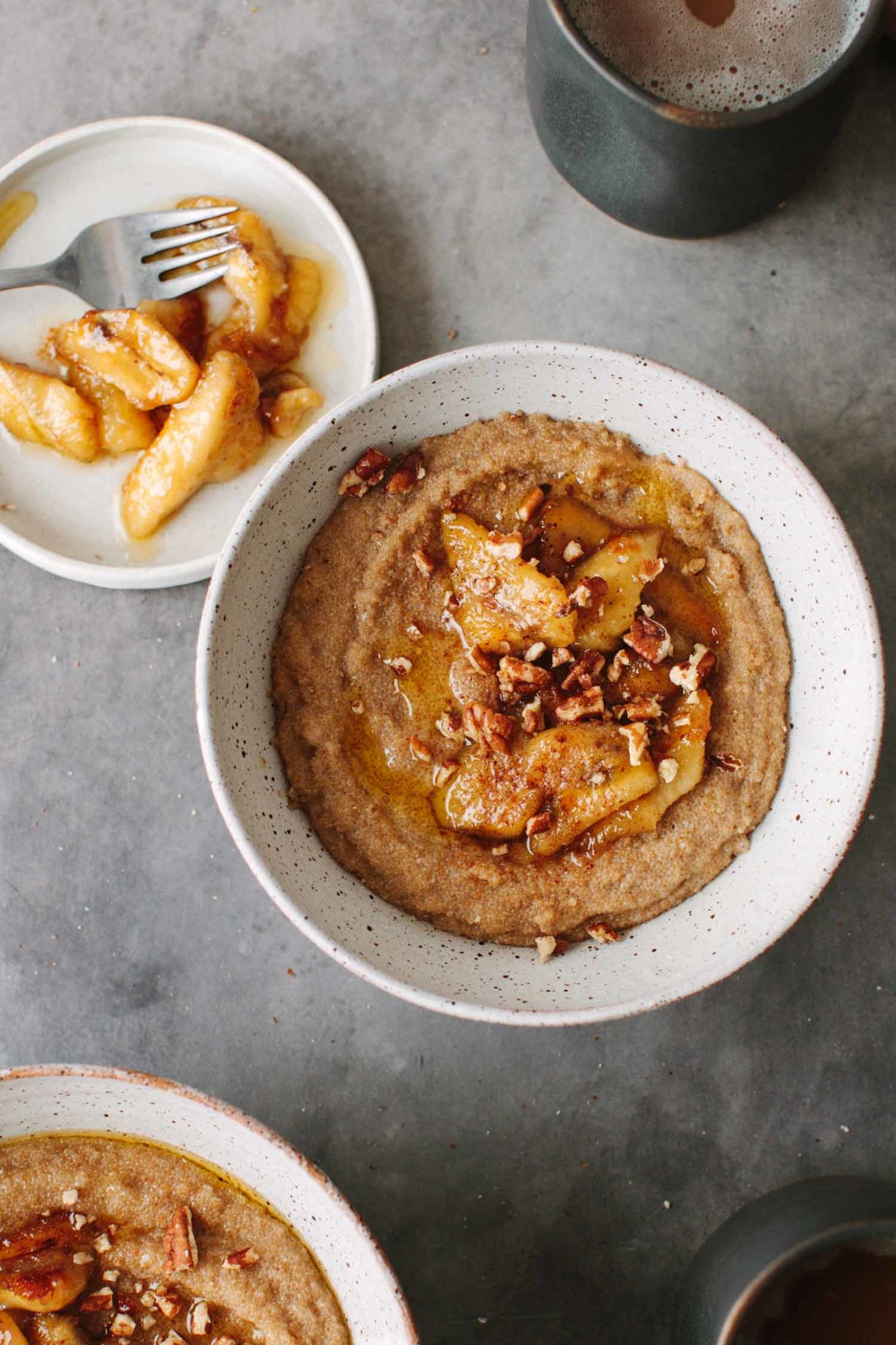 Overhead photograph of Amaranth Porridge with Caramelized Bananas and an extra white plate with caramelized bananas.