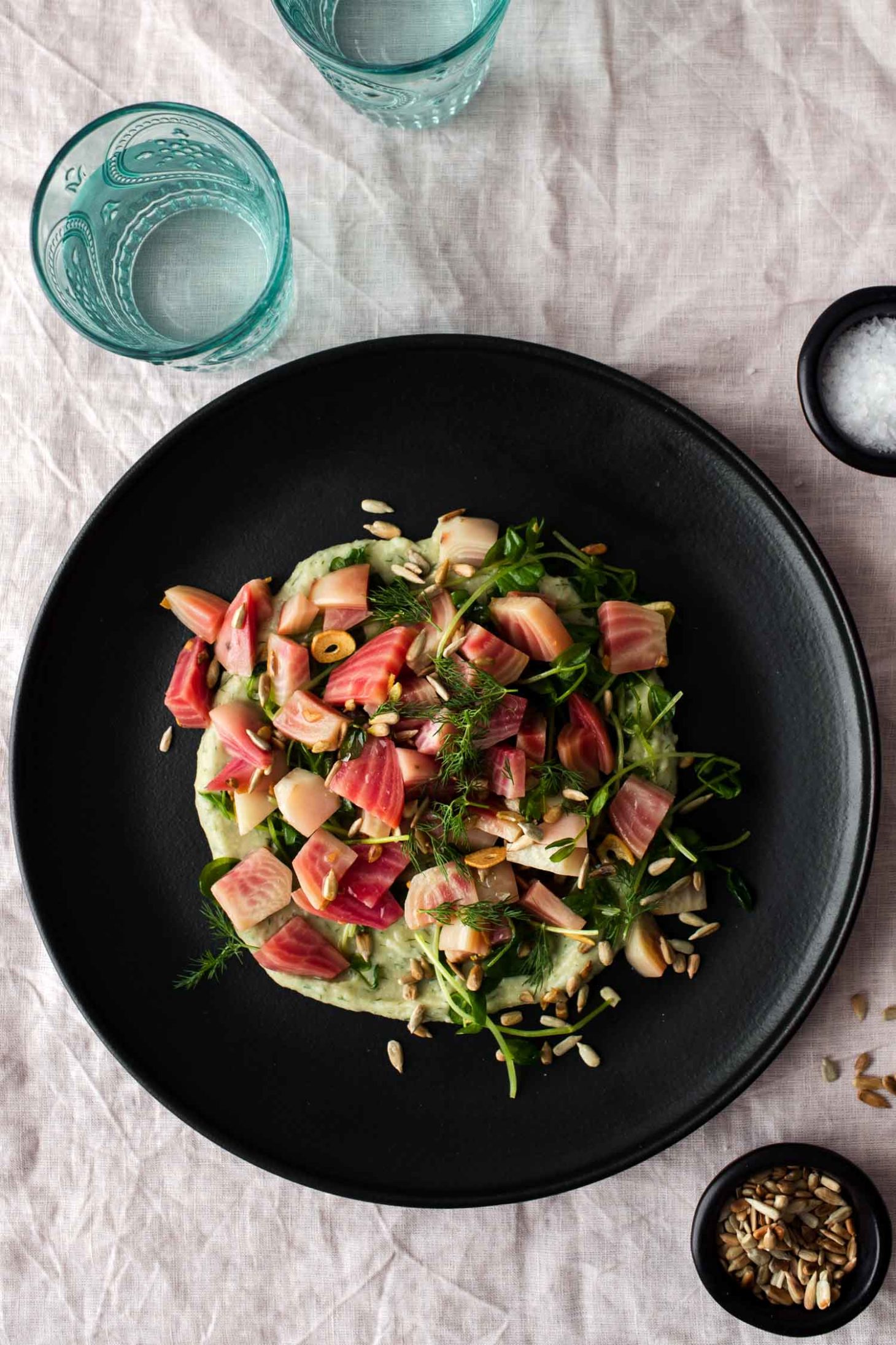 Overhead photograph of steamed chioggia beets on a black plate.