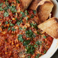 Close-up photograph of an overhead white dutch oven with red lentils, tomato sauce, and cauliflower.