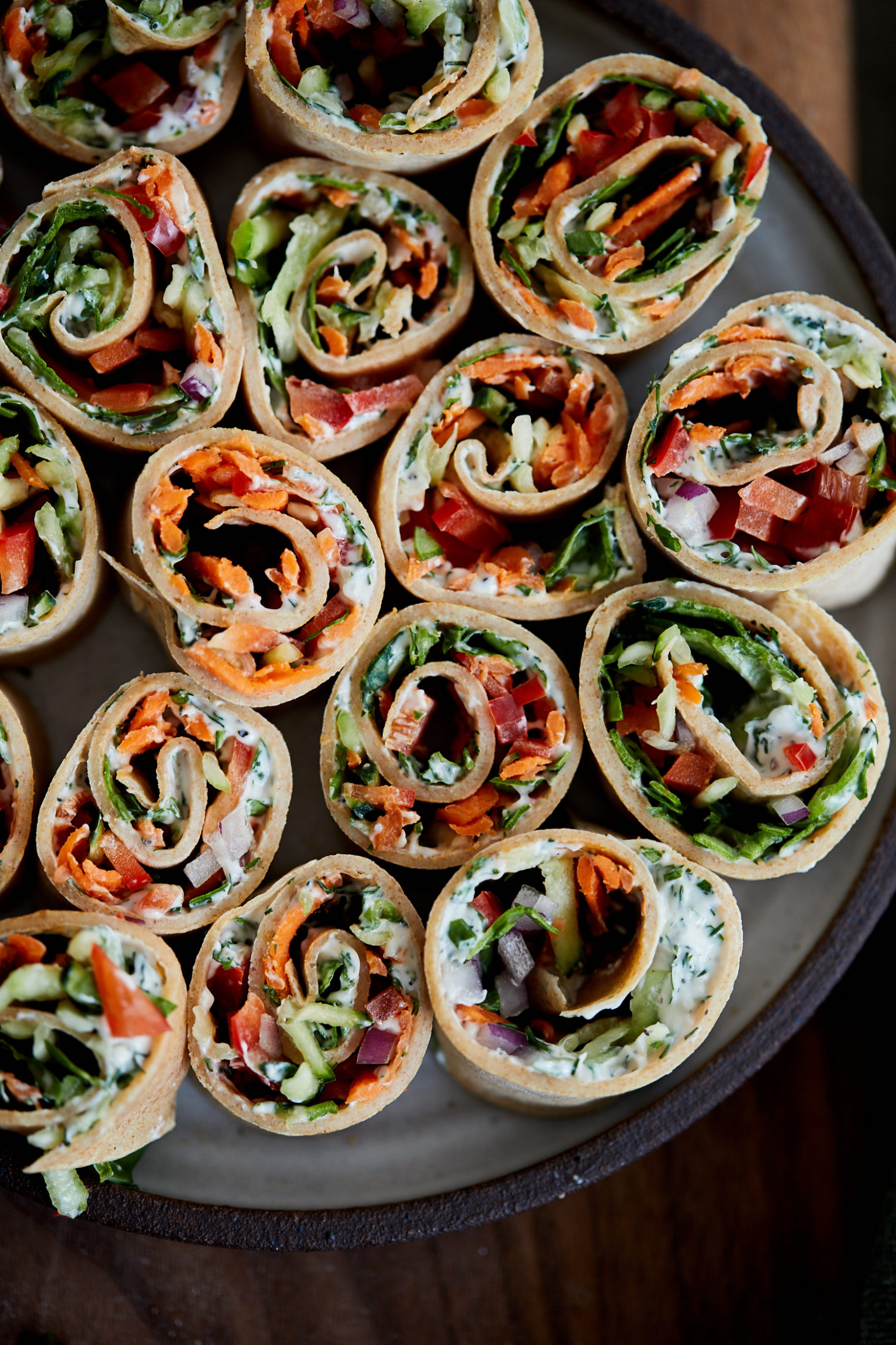 Overhead photograph of cut-open roll-ups showing vegetables, cream cheese, and crepes.