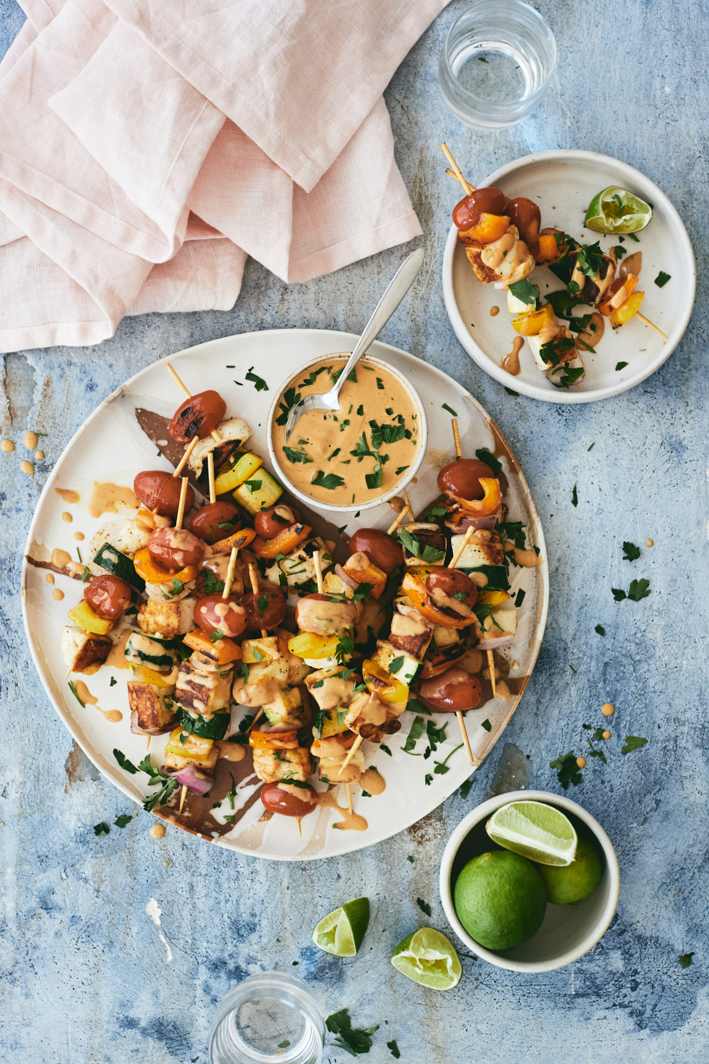 Overhead photograph of halloumi and summer vegetable skewers topped with a chipotle peanut sauce