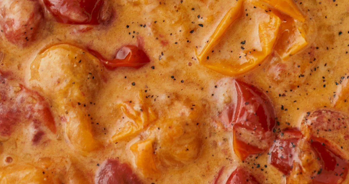 Close-up image of a sauce with tomatoes and parmesan.