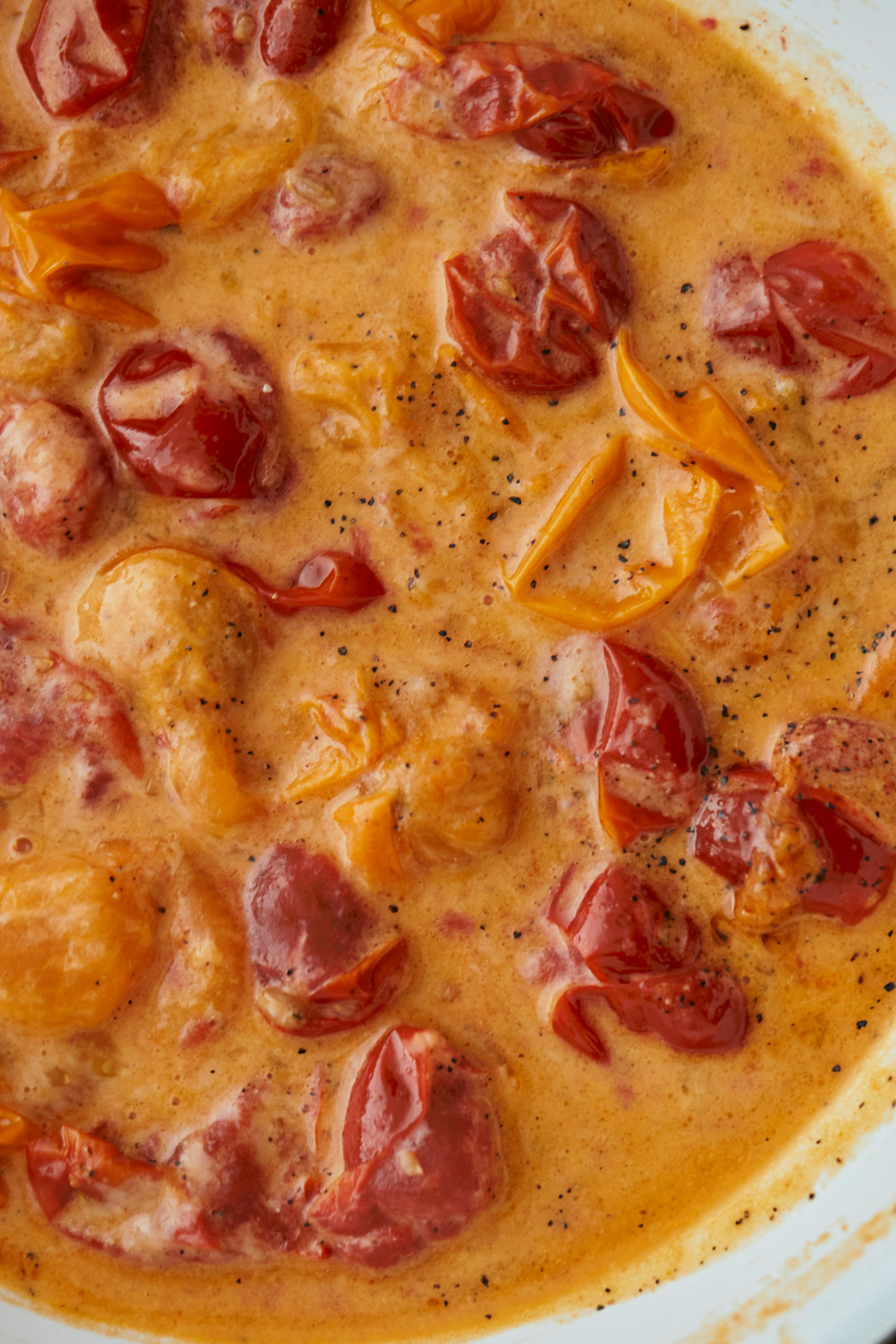 Close-up image of a sauce with tomatoes and parmesan.