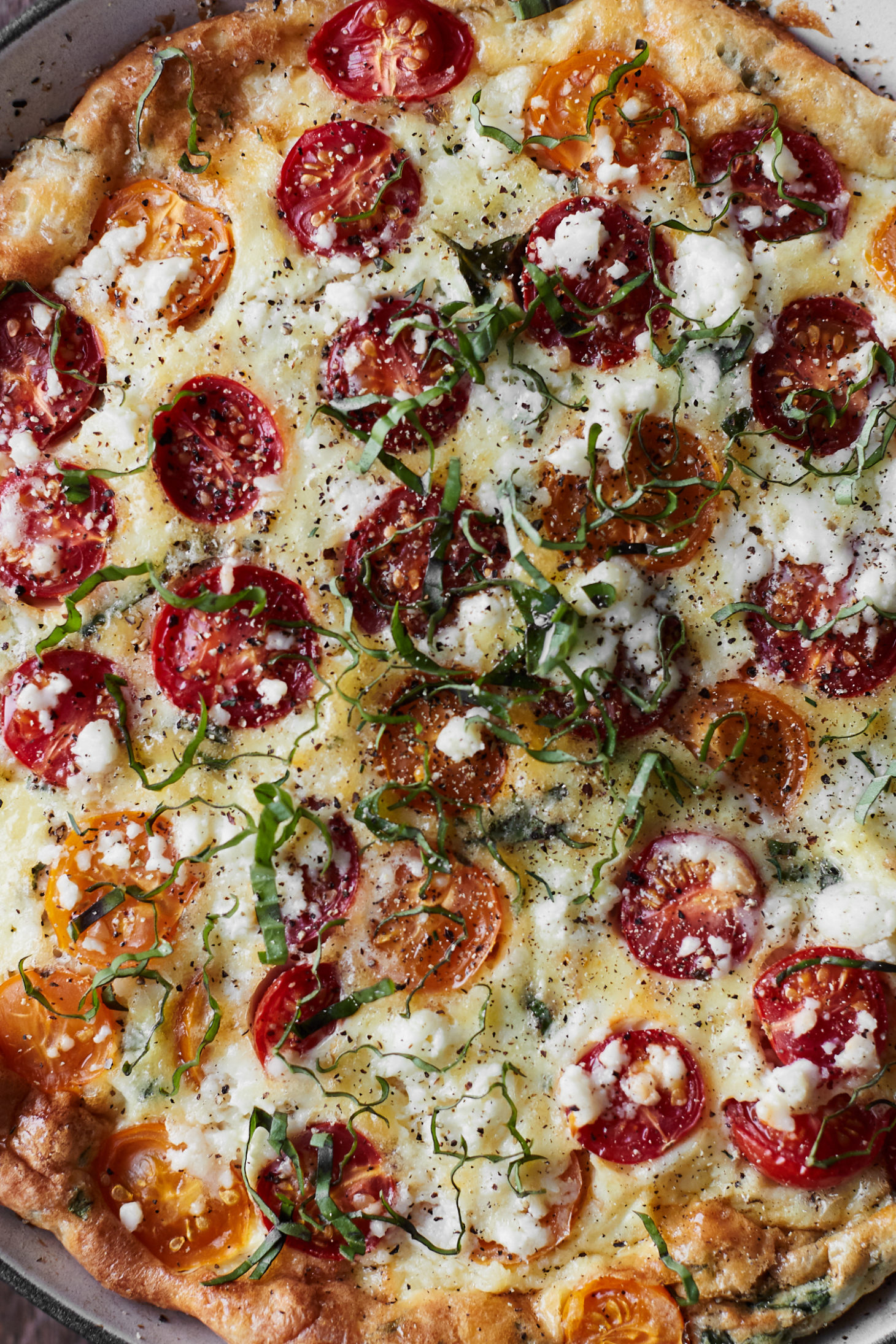Close-up photograph of a frittata with cherry tomatoes, bulgur, and feta.