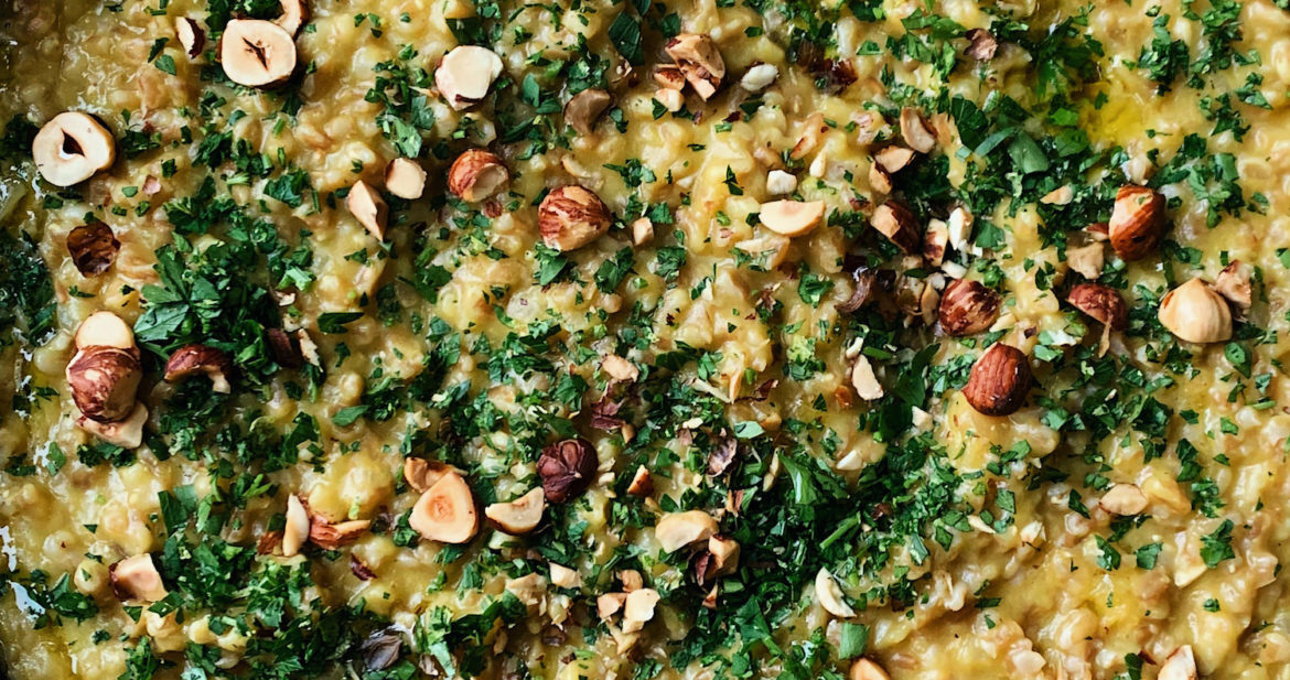 Close-up photograph of farro risotto with acorn squash puree and topped with toasted hazelnuts and gremolata