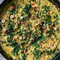 Close-up photograph of farro risotto with acorn squash puree and topped with toasted hazelnuts and gremolata