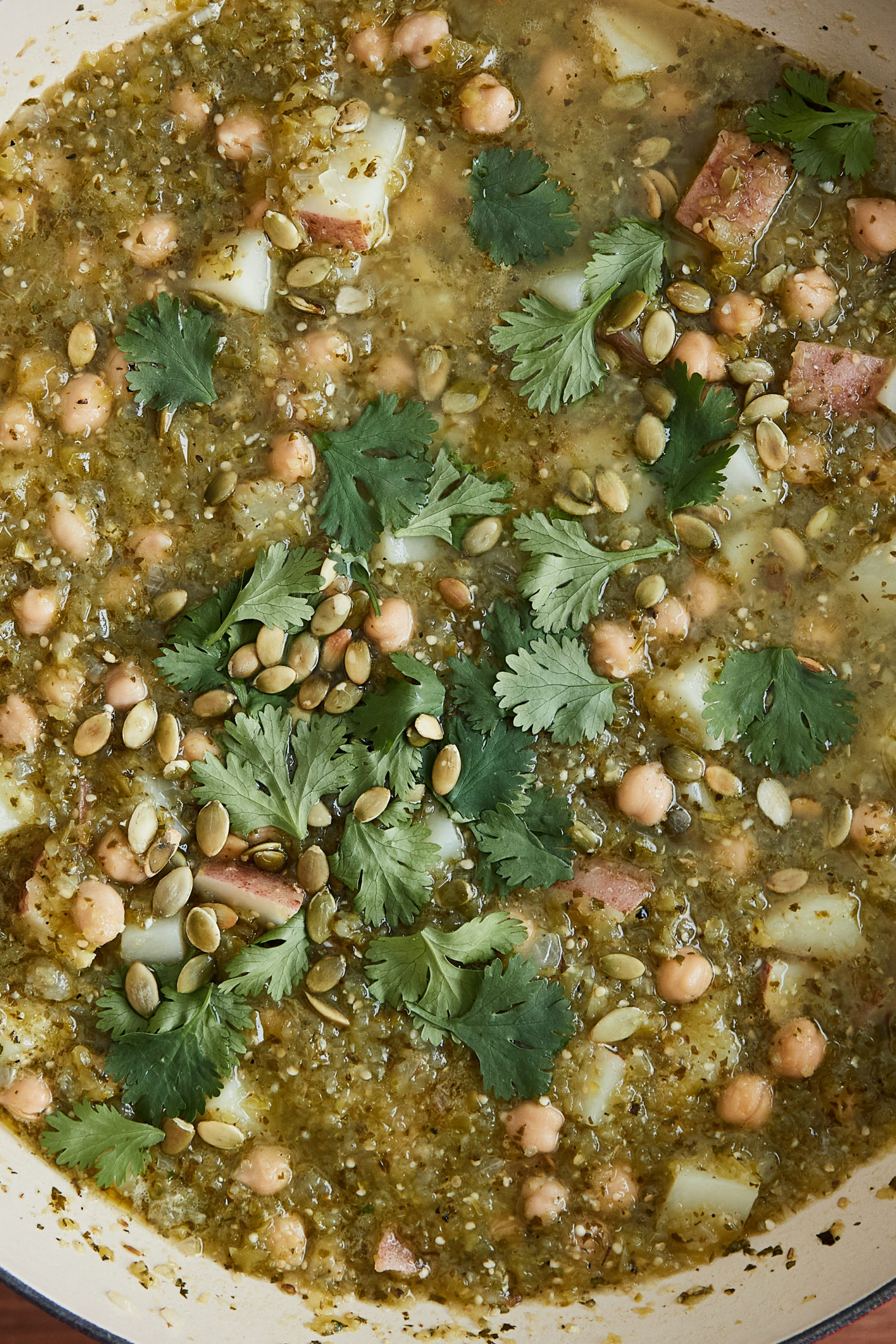 A close-up photo of green chickpea chili topped with cilantro and pepitas.