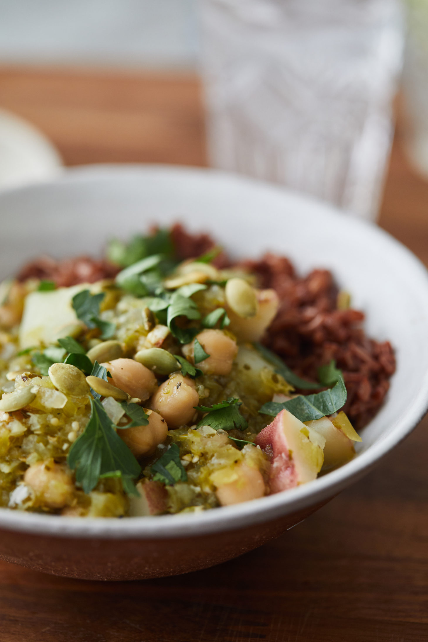 Side photograph of a green chili with chickpeas in a white bowl.