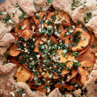 Close-up image of a whole wheat galette with sweet potatoes on a blue plate.