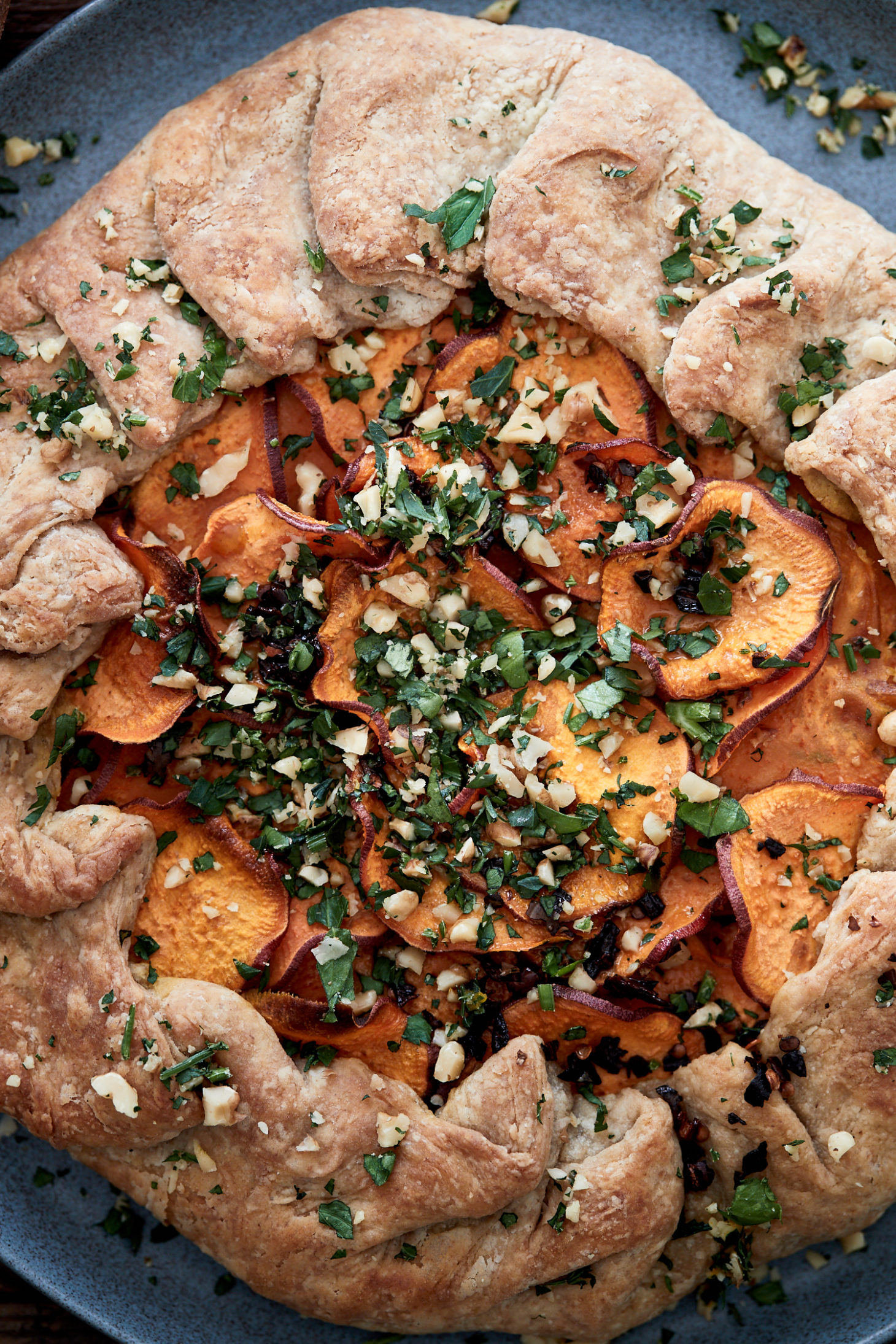 Close-up image of a whole wheat galette with sweet potatoes on a blue plate.