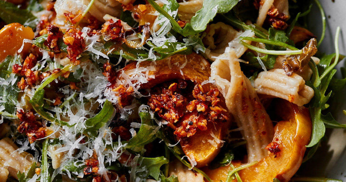 Close-up image of pasta with arugula and delicata squash.