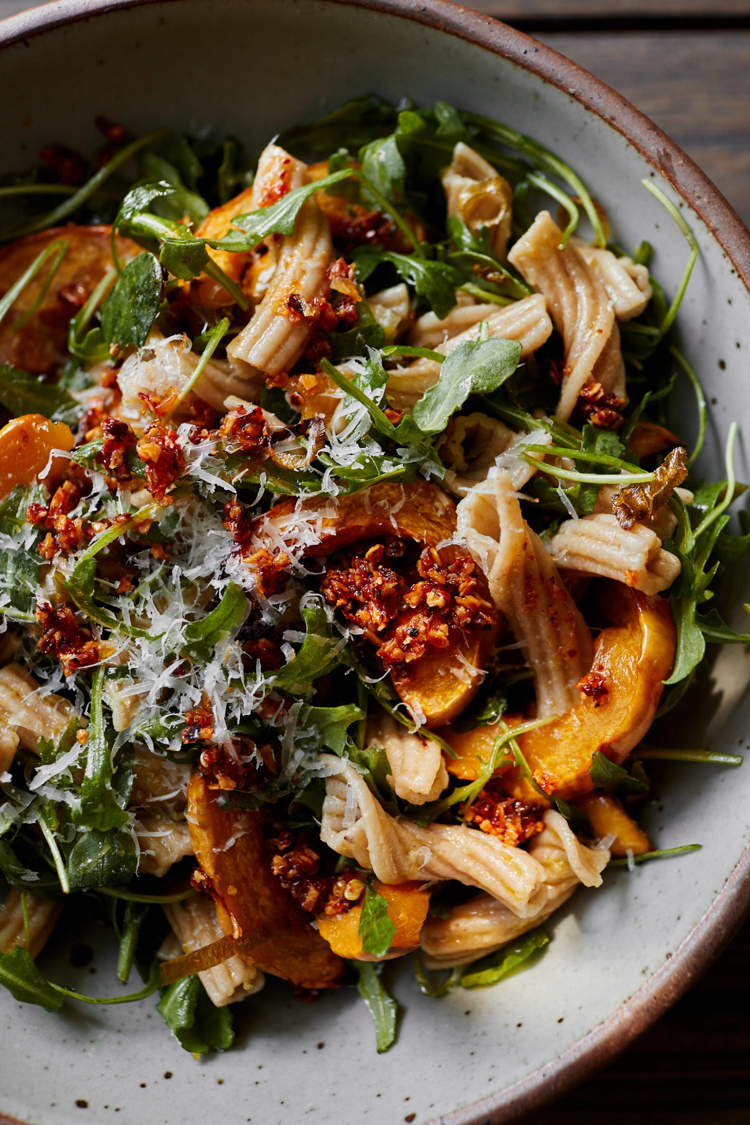 Close-up image of pasta with arugula and delicata squash.