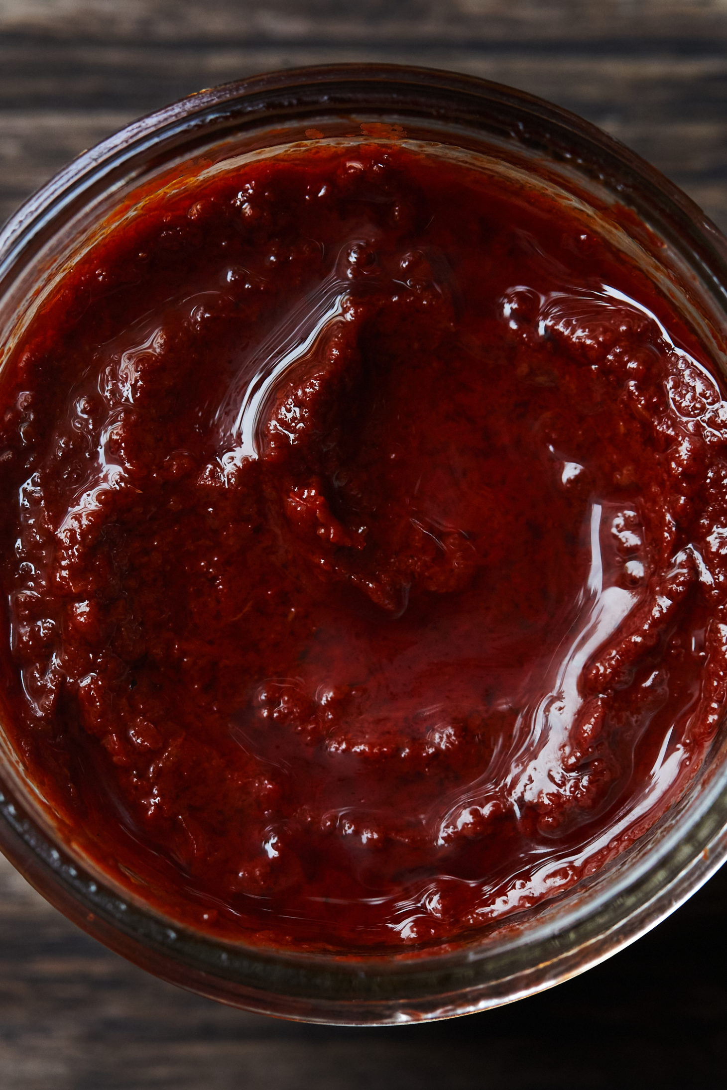 Close-up of a reddish paste in a clear jar.