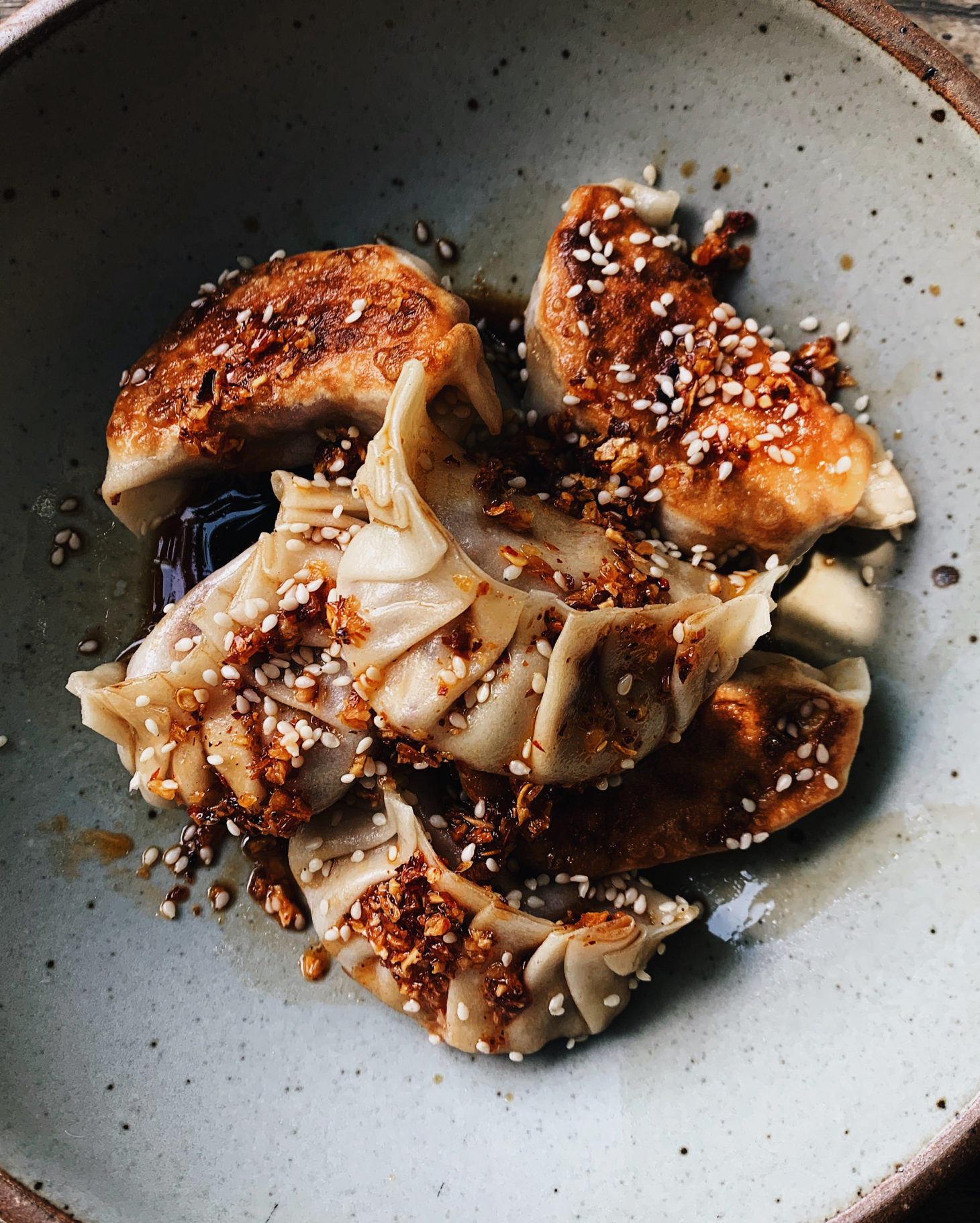 Close-up photo of pleated potstickers in a grey bowl.