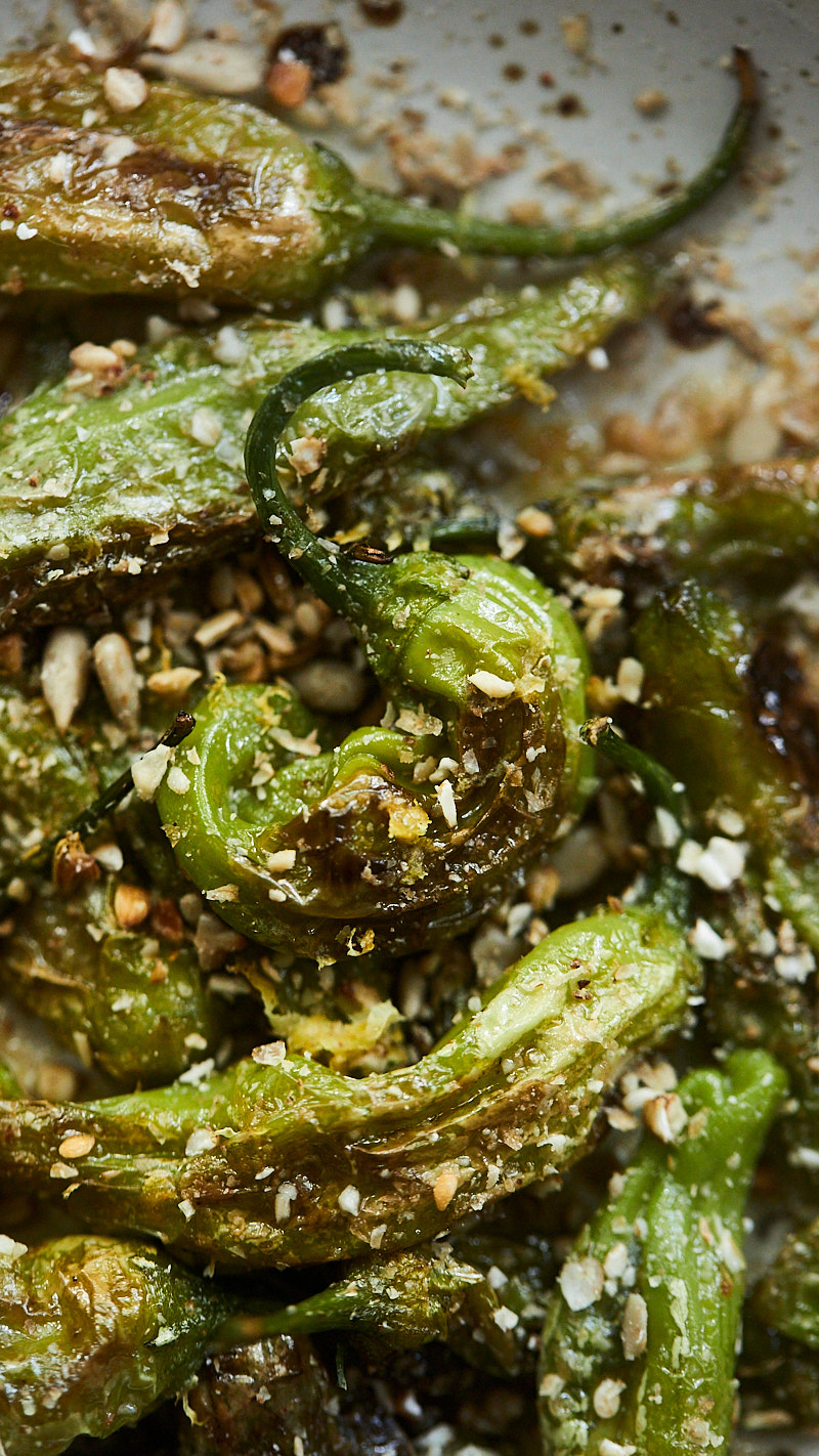 Close-up of blistered shishito peppers dusted with a crushed buckwheat mixture
