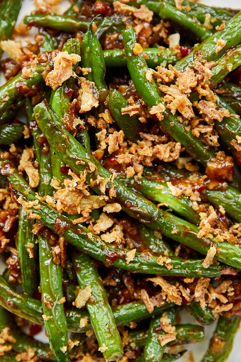 a close-up of grilled green beans in a chile soy sauce.