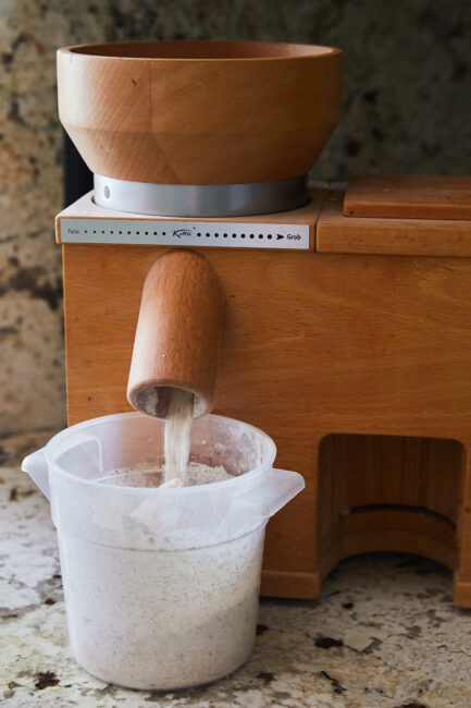 Milling Flour: an image of grains being milled in a komo grain mill