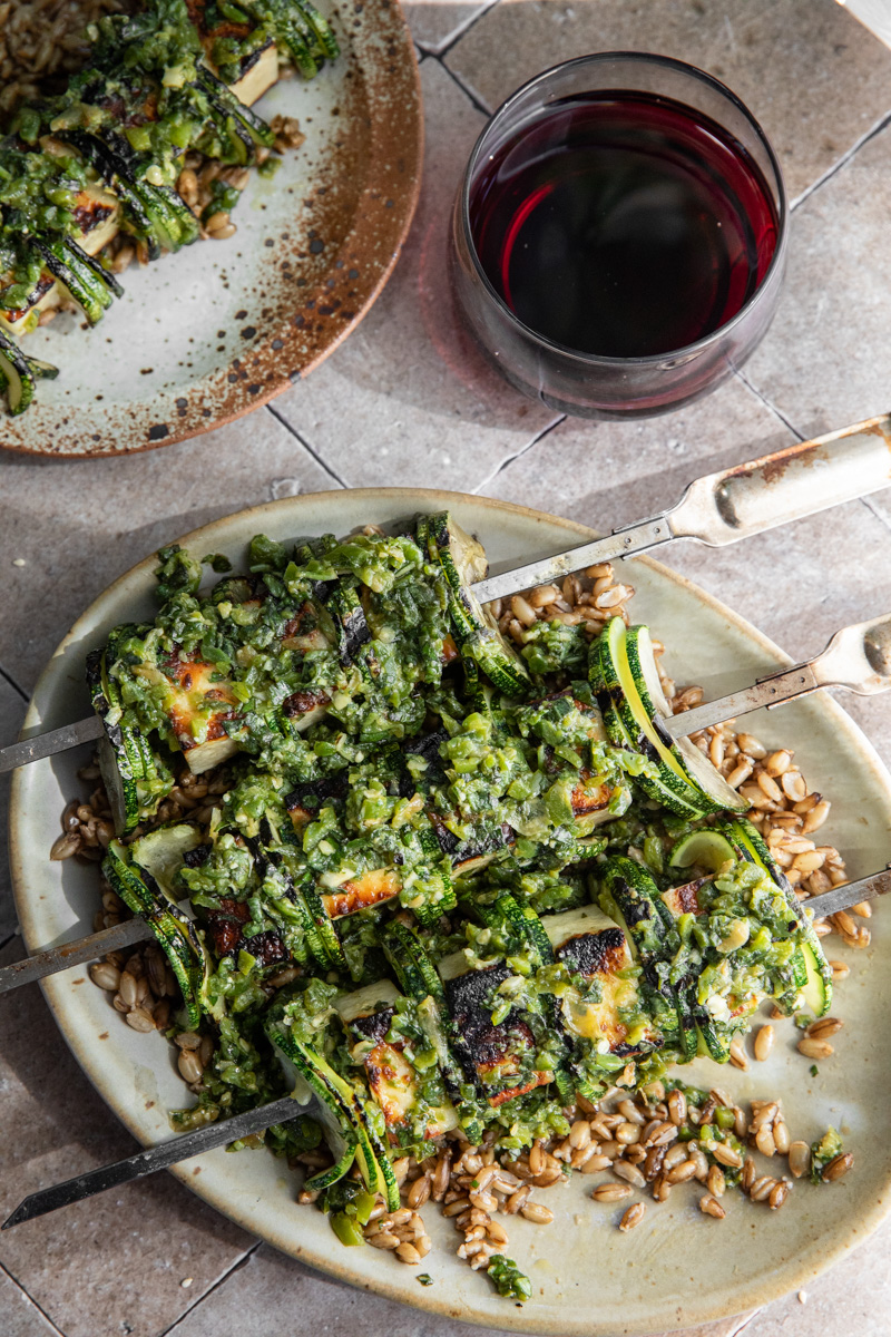 Image of grilled paneer skewers with zucchini, poblano sauce, and grains.