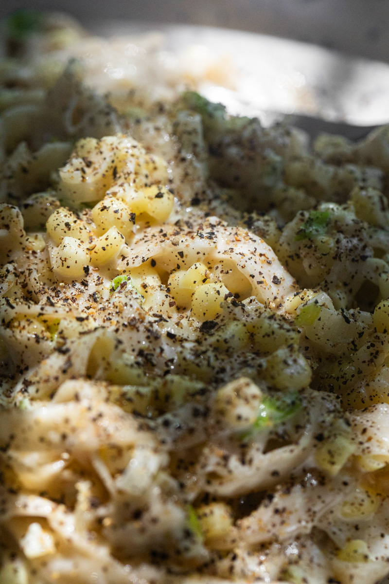 close-up photo of sweet corn pasta with lots of black pepper on top