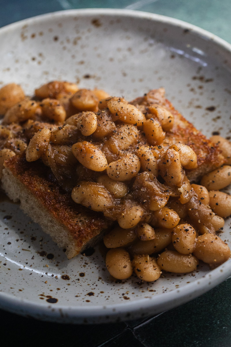 French Onion-Inspired Beans served over toast in a speckled bowl.