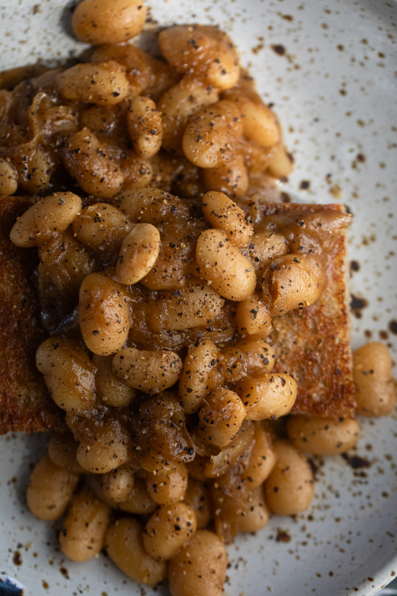 overhead image of beans in a thick gravy and speckled with ground black pepper