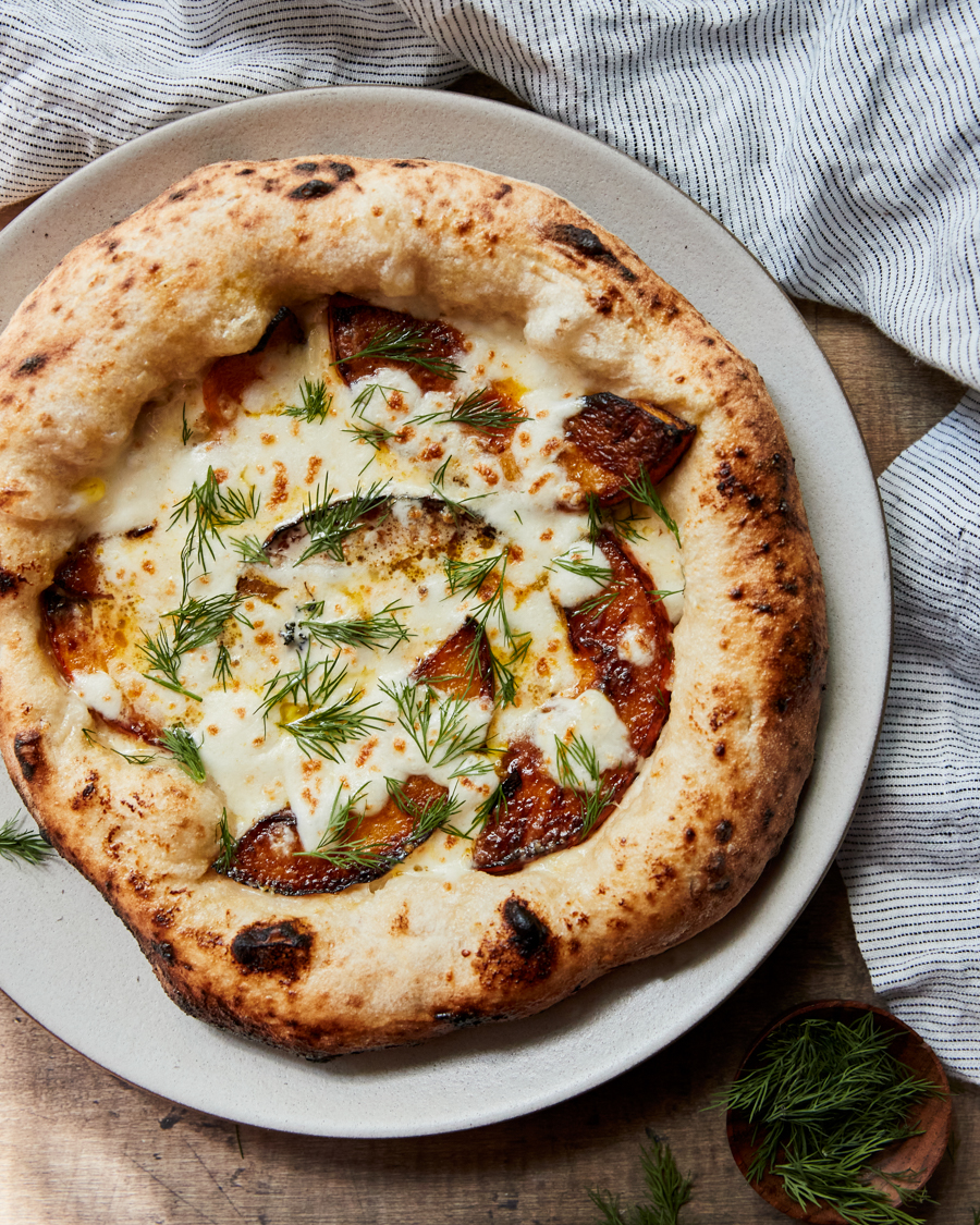 Close-up of a squash pizza with wedges of kabocha squash and a cream sauce.