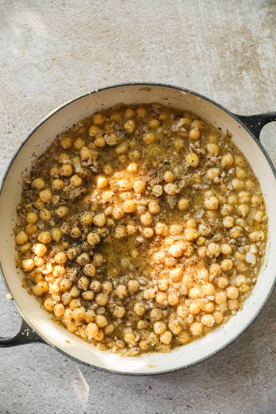 Image of a braiser filled with chickpeas and emmer in broth